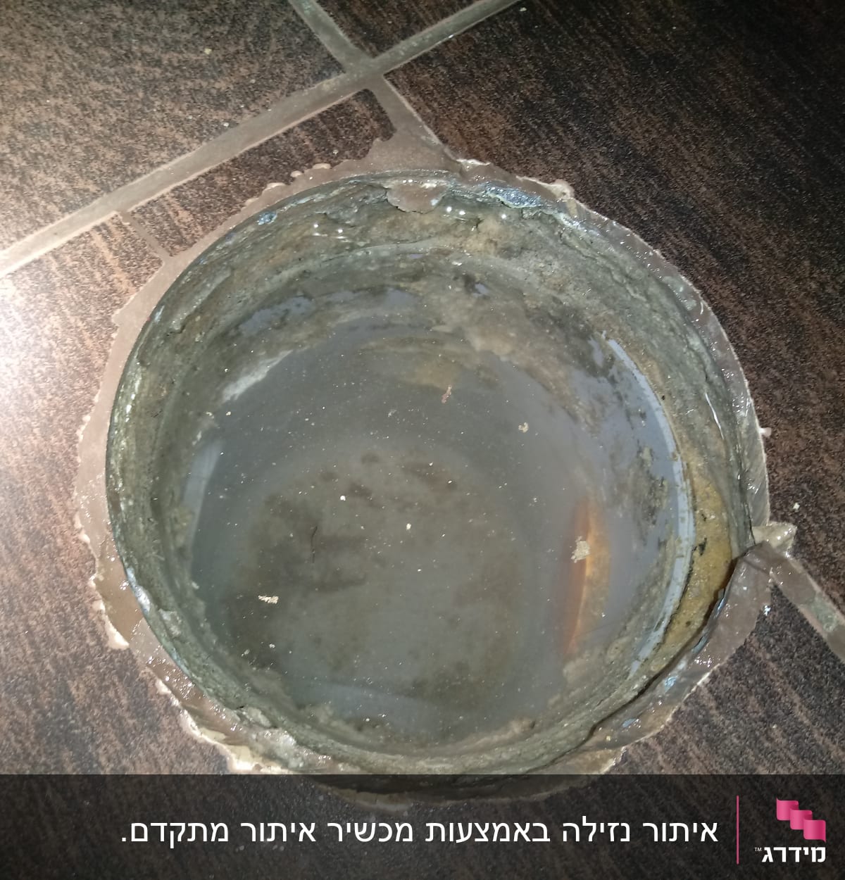 פתח ניקוז עם מים עומדים על רצפה כהה